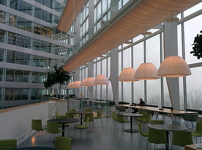 man sitting alone inside building with chairs and tables and lights turned on thumbnail