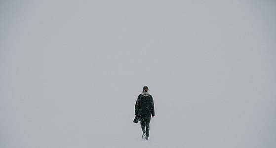 person with scarf walking on snow filled area thumbnail