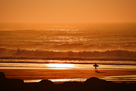 person holding surfboard on seashore during golden hour thumbnail