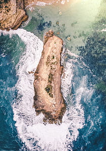 brown rock formation in the middle of body of water thumbnail