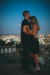 focus photo of man holding woman while standing on brown soil thumbnail