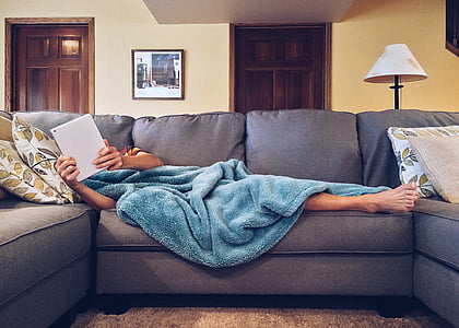 person covered with blue blanket lying on gray sofa thumbnail