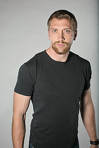 man in black crew-neck t-shirt standing behind white wall paint thumbnail