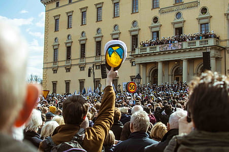 person holding raising cap with crowded people thumbnail