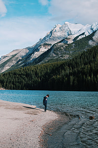 person in black jacket standing in front of calm body of water thumbnail