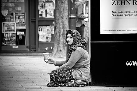 grayscale photo of woman holding cup sitting on floor thumbnail