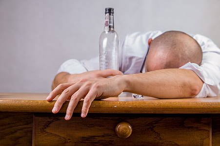 man leaning on desk while holding bottle thumbnail