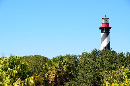 white and red lighthouse near trees thumbnail