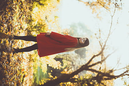 woman standing on dried leaves near trees thumbnail