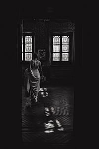 grayscale photo of woman wearing dress and holding bouquet of flowers inside room thumbnail