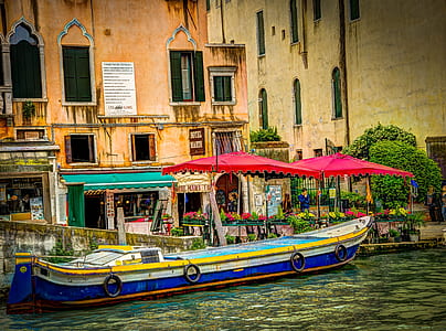 blue and yellow canoe parked near buildings thumbnail