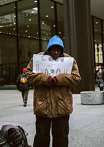 man holding printing paper with cold hungry text standing outside building thumbnail