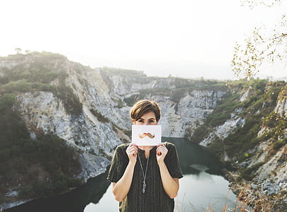 person holding white paper near body of water thumbnail