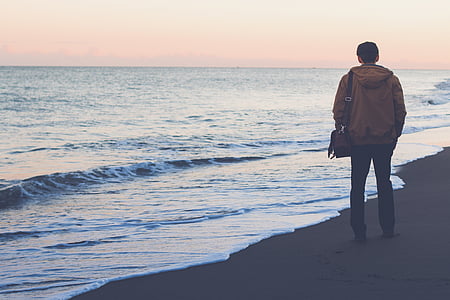 man standing on seashore while looking at waves thumbnail