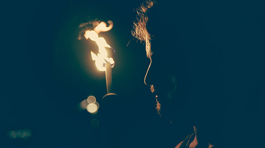 man standing near lighted torch outdoors thumbnail