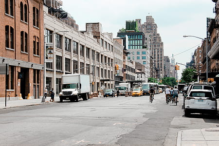 photo of people walking and cycling near road between buildings thumbnail