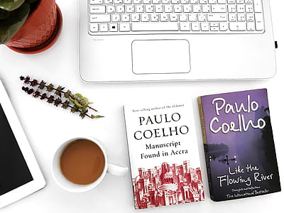 two Paulo Coelho books on table beside mug filled with coffee thumbnail