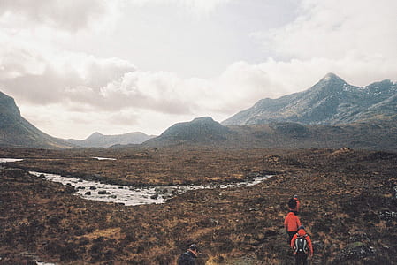 three men hiking while walking in front of mountain at daytime thumbnail