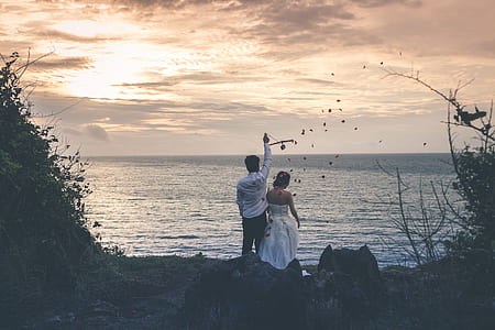 bride and groom standing in front of body of water thumbnail