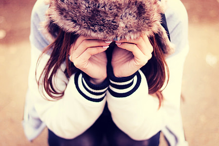 woman in black and white letterman's jacket vowing with hands on eyes during day time thumbnail