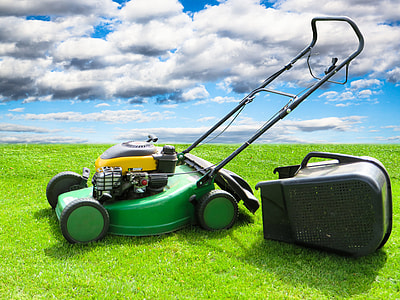 green and yellow push mower on green grass field under clouded sky thumbnail