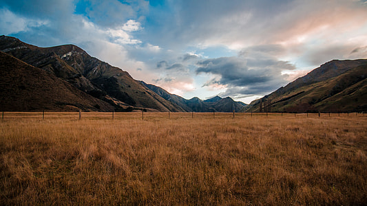 brown wooden fence in the middle of brown grass field with mountain range view during daytime thumbnail