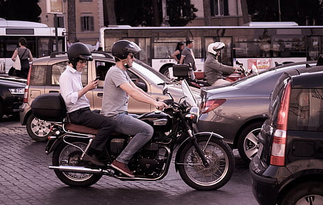 two men riding on motorcycle in the middle of a tight traffic during day thumbnail