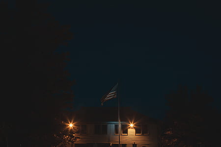 flag of U.S.A. on flagpole beside house at nighttime thumbnail