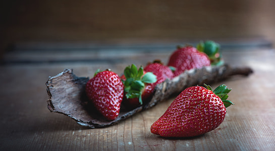 person taking photo of strawberry in tilt shift photography thumbnail