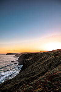 rock formation near sea under blue sky during daytime thumbnail
