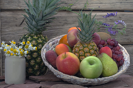 assorted fruits in brown wicker basket beside white Chrysanthemum flower centerpiece thumbnail