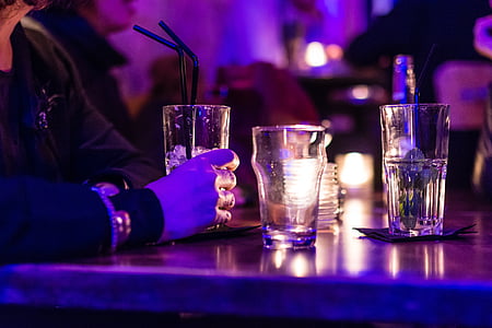 person about to grab clear drinking glass with black straw thumbnail