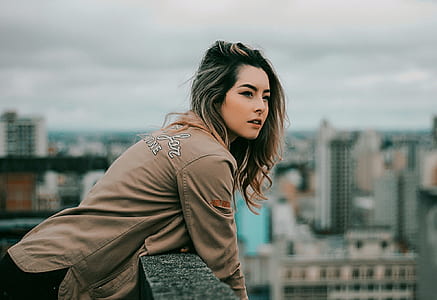 woman leaning on gray fence on top of building thumbnail