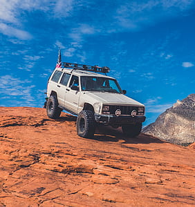 gray Jeep Cherokee on top of brown mountain under blue sky thumbnail