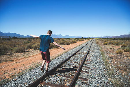man standing on train rail at daytime thumbnail