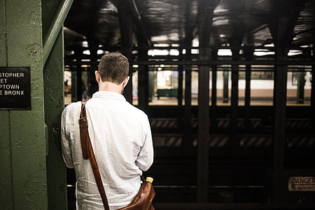 man in white dress shirt standing near green metal post thumbnail