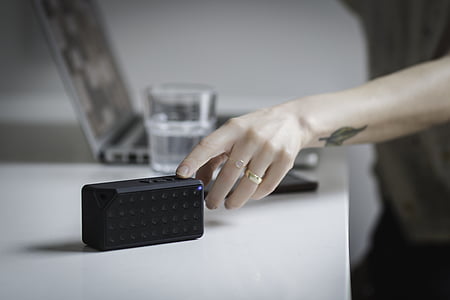 person touching speaker on white table thumbnail