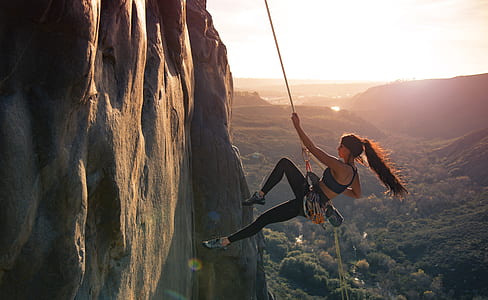 woman in rappelling on mountain during daytime thumbnail