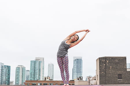 woman in grey tank top and purple pants bending her body thumbnail