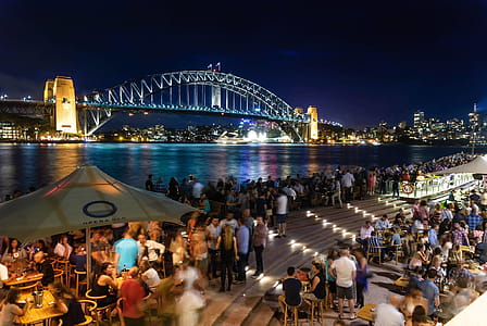 People Sitting and Standing Near Bridge during Nighttime thumbnail