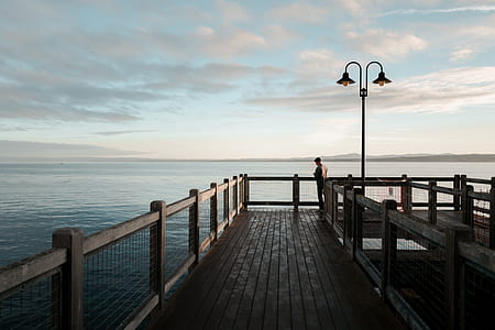 person standing beside body of water under blue sky thumbnail