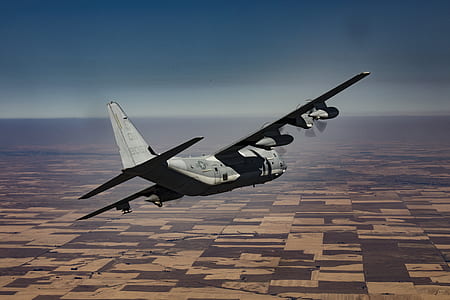 gray airplane flying across land thumbnail