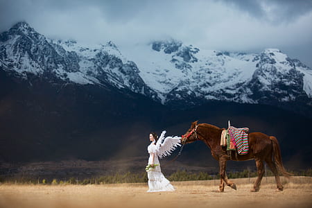 woman in angel costume walks in front of brown horse thumbnail