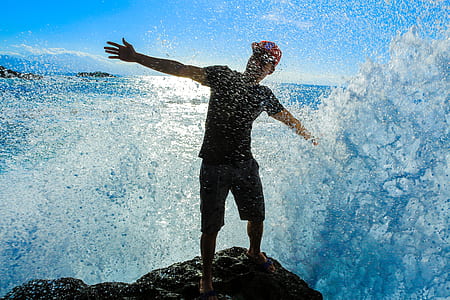 man standing on top of rock near seashore thumbnail