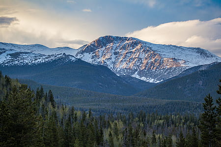 white and brown rocky mountain surrounded green pine trees during daytime thumbnail