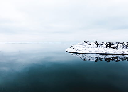 islet surrounded with calm water under cloudy sky thumbnail