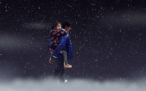 person wearing blue jacket carrying girl wearing black and pink jacket on star background thumbnail
