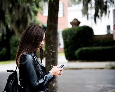 Woman in Black Leather Jacket Holding Smartphone thumbnail