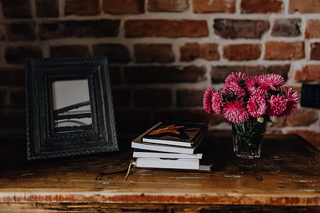 Photo frame, books and pink flowers in a vase on a wooden commode thumbnail