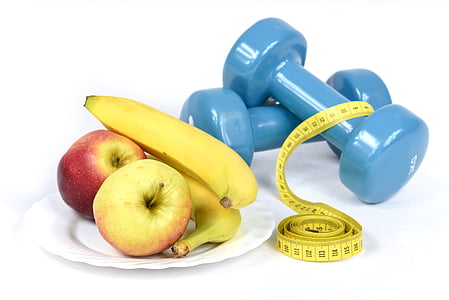 two apples and two bananas served on white plate near two blue fixed weight dumbbells and tape measure thumbnail